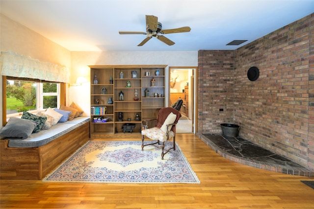 living area with visible vents, a ceiling fan, and wood finished floors