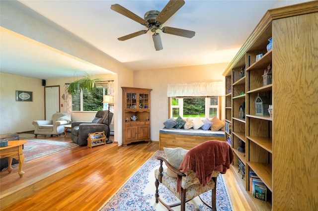 living area with light wood-style floors and a ceiling fan