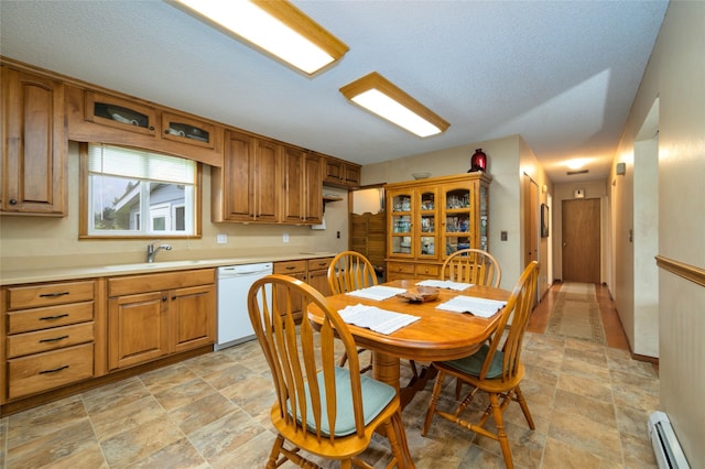 kitchen with brown cabinetry, white dishwasher, a sink, light countertops, and a baseboard heating unit