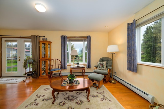 living area with a baseboard heating unit, wood finished floors, and french doors