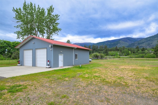 exterior space with a lawn, fence, a mountain view, an outdoor structure, and a garage