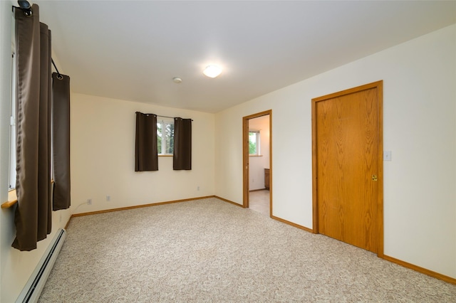 unfurnished bedroom featuring a baseboard heating unit, light carpet, and baseboards