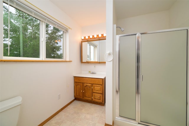 bathroom featuring vanity, toilet, baseboards, and a stall shower