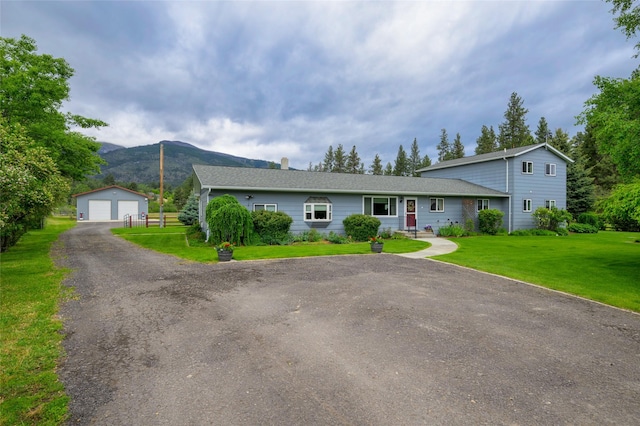 view of front of house featuring an outbuilding, a mountain view, a detached garage, and a front lawn