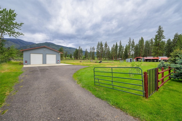 view of front of property with an outbuilding, a mountain view, a front yard, and fence