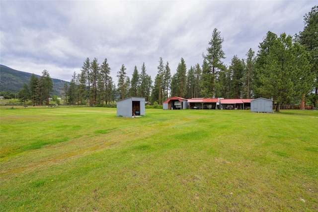 view of yard featuring a storage shed, an outbuilding, a mountain view, and a detached garage