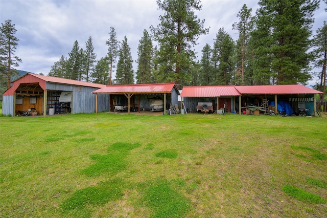 exterior space with a yard, a detached garage, an outbuilding, and metal roof