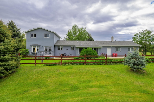 rear view of house with a lawn and fence