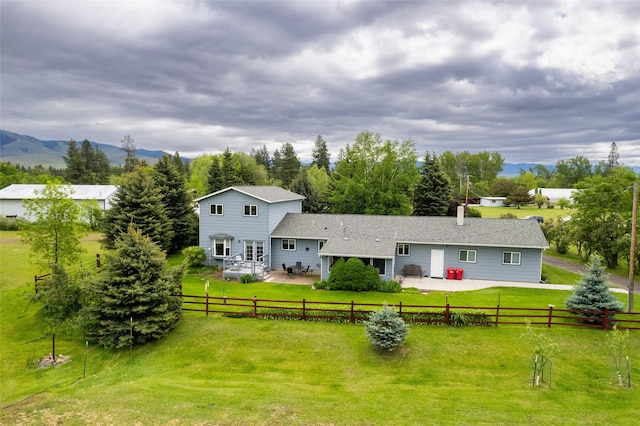 rear view of property featuring a patio area, a lawn, a mountain view, and a fenced backyard