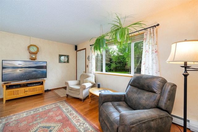 interior space with wood finished floors, baseboard heating, and a textured ceiling