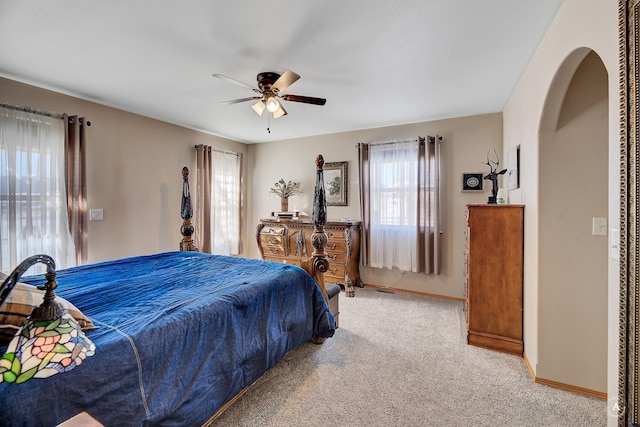 carpeted bedroom featuring arched walkways, ceiling fan, and baseboards