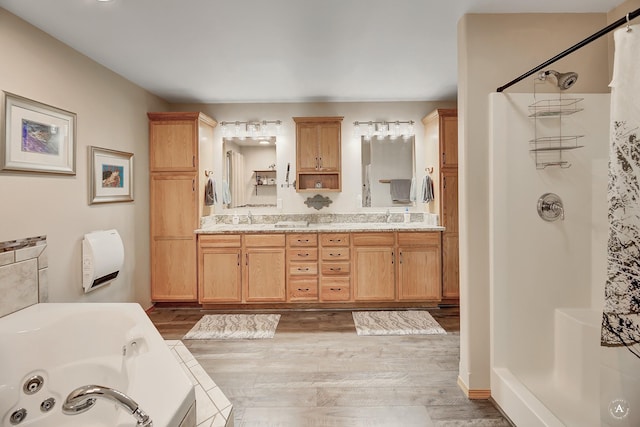 bathroom featuring a shower stall, wood finished floors, a whirlpool tub, and a sink