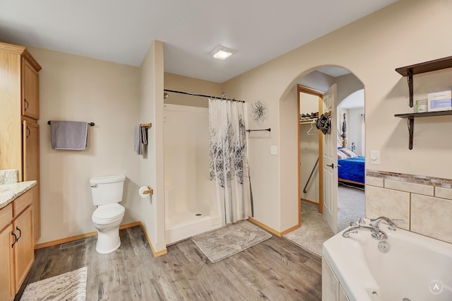 full bathroom featuring a stall shower, toilet, a tub with jets, and wood finished floors