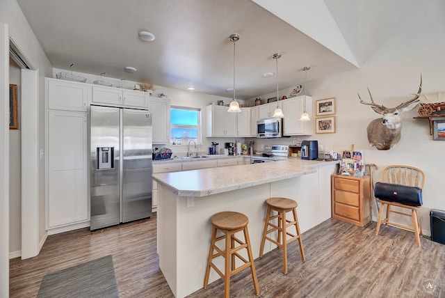 kitchen with light wood-style flooring, a sink, white cabinetry, stainless steel appliances, and a peninsula