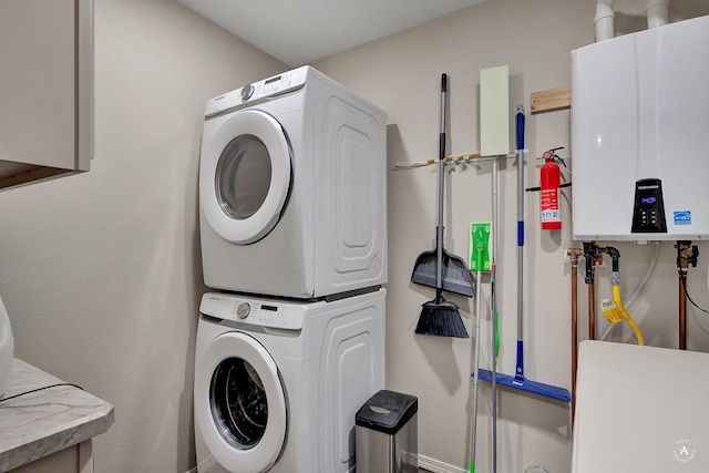 washroom featuring tankless water heater, stacked washer and clothes dryer, and laundry area