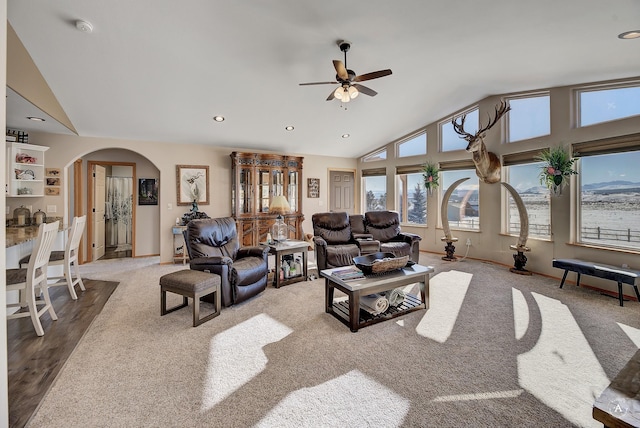 carpeted living room featuring a ceiling fan, baseboards, high vaulted ceiling, recessed lighting, and arched walkways