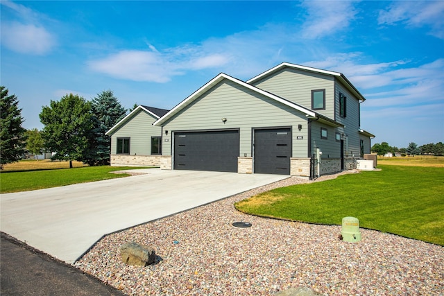 view of front facade with stone siding, an attached garage, driveway, and a front yard