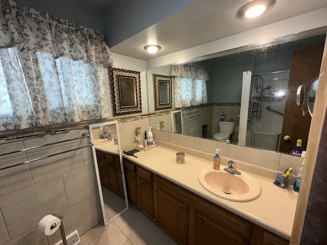 bathroom with toilet, tile walls, a shower stall, tile patterned flooring, and vanity