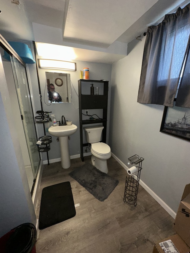 full bathroom with toilet, a stall shower, a sink, wood finished floors, and baseboards