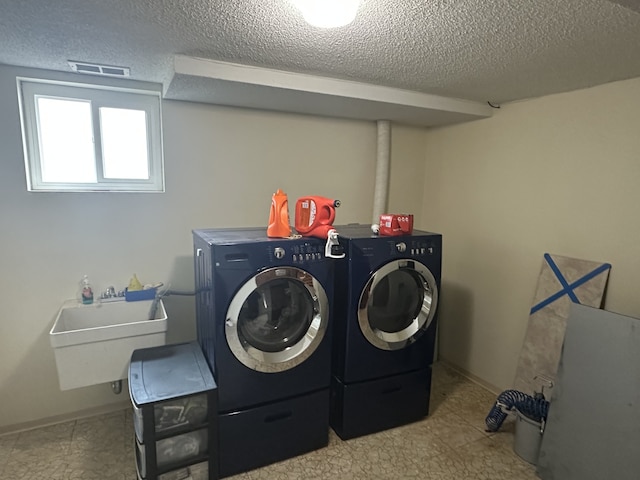 laundry area with laundry area, a sink, a textured ceiling, and separate washer and dryer