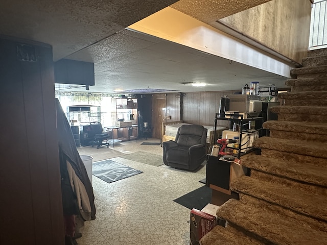 basement with stairs, tile patterned floors, and wood walls