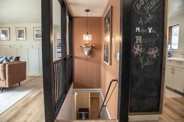 hall with an upstairs landing and light wood-style floors