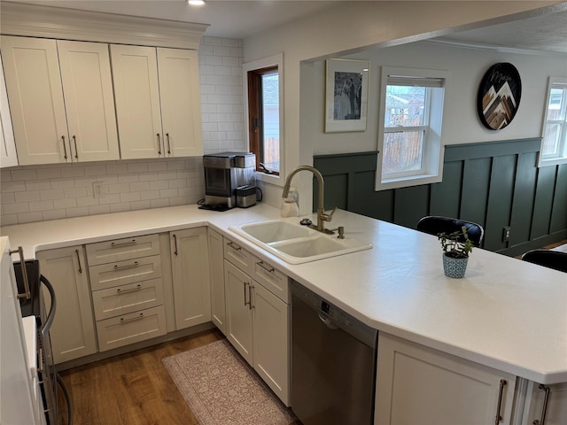 kitchen featuring a peninsula, stainless steel dishwasher, dark wood-style floors, plenty of natural light, and a sink