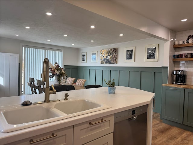 kitchen featuring a wainscoted wall, dishwasher, recessed lighting, wood finished floors, and a sink