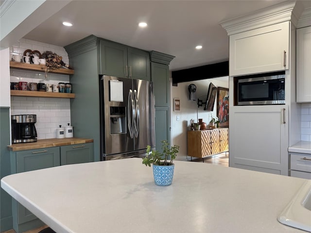 kitchen with decorative backsplash, recessed lighting, appliances with stainless steel finishes, and butcher block counters