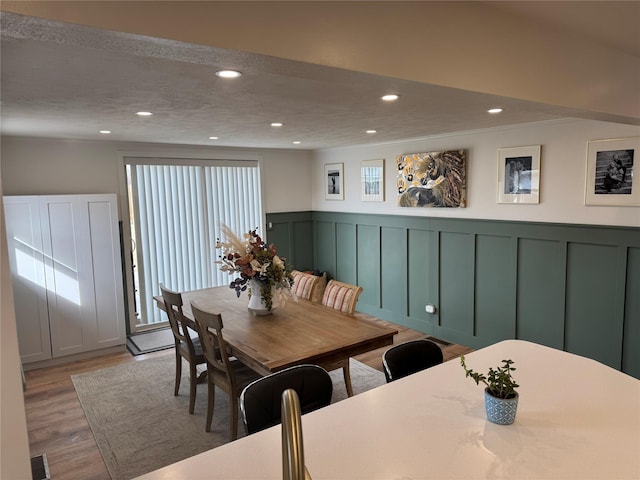 dining area with visible vents, recessed lighting, wainscoting, a decorative wall, and light wood-type flooring