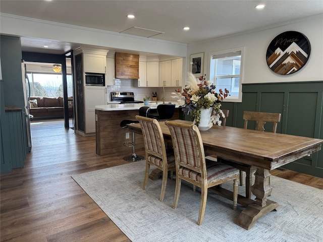 dining room with plenty of natural light, ornamental molding, a wainscoted wall, and wood finished floors