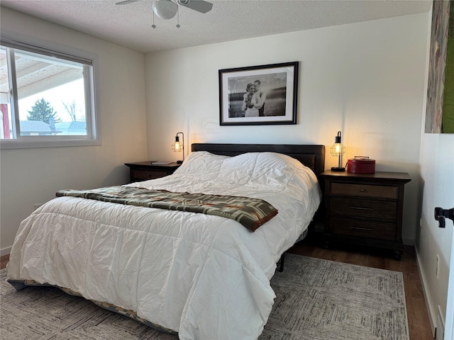 bedroom with a textured ceiling, baseboards, and wood finished floors