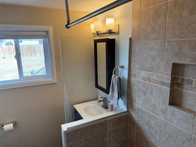 bathroom featuring tiled shower and a sink