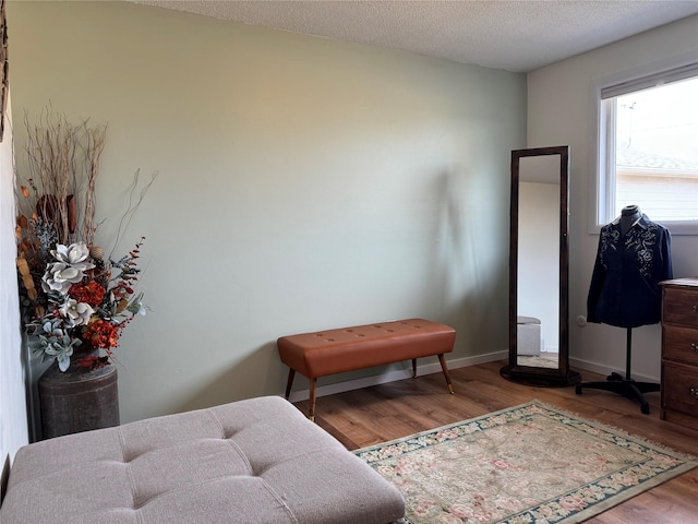 bedroom with baseboards, a textured ceiling, and wood finished floors