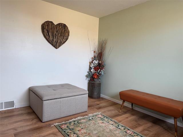 sitting room featuring wood finished floors, visible vents, and baseboards