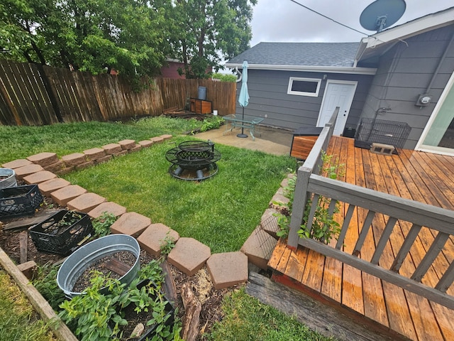 view of yard featuring a wooden deck, fence, and an outdoor fire pit