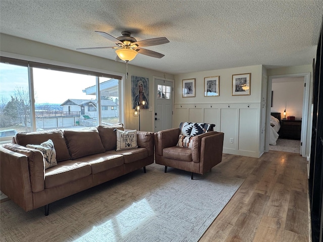 living room with light wood-style floors, a ceiling fan, and a textured ceiling