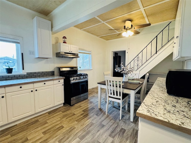 kitchen featuring stainless steel range with gas cooktop, light countertops, under cabinet range hood, white cabinetry, and light wood-type flooring