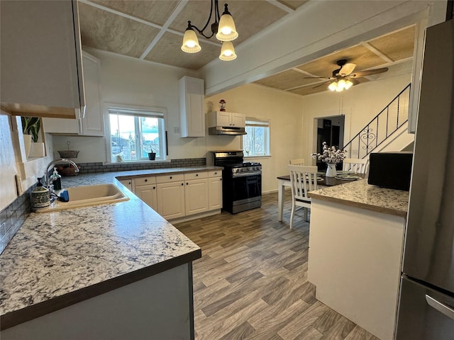 kitchen with light wood-style flooring, a sink, stainless steel appliances, white cabinetry, and ceiling fan with notable chandelier