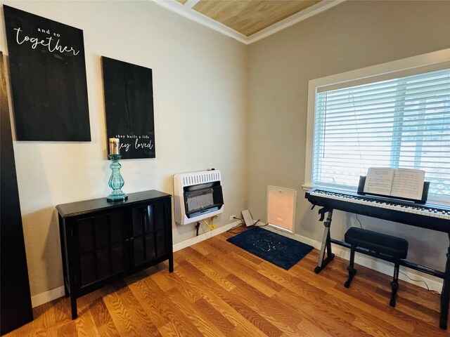 living area featuring heating unit, wood finished floors, baseboards, and ornamental molding