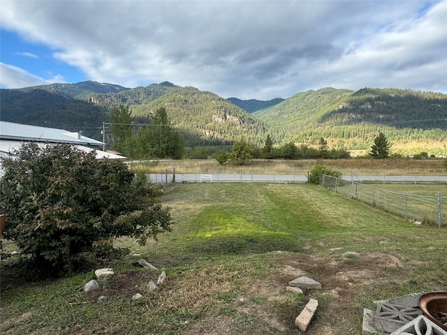 view of yard featuring a rural view, fence, and a mountain view