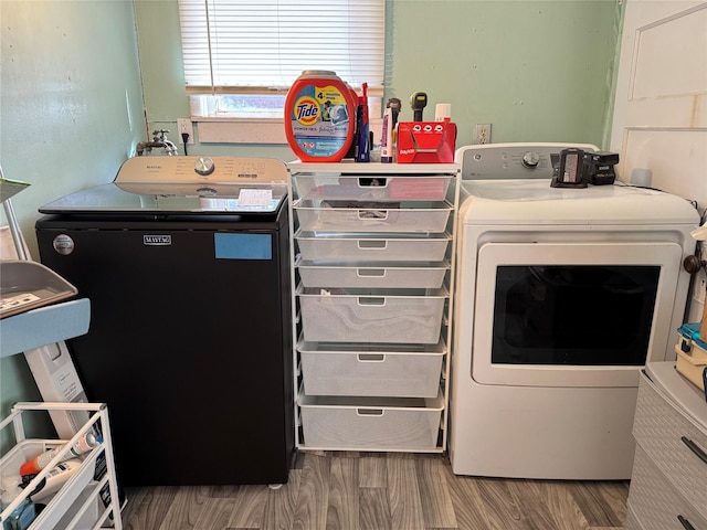 clothes washing area featuring separate washer and dryer, wood finished floors, and laundry area