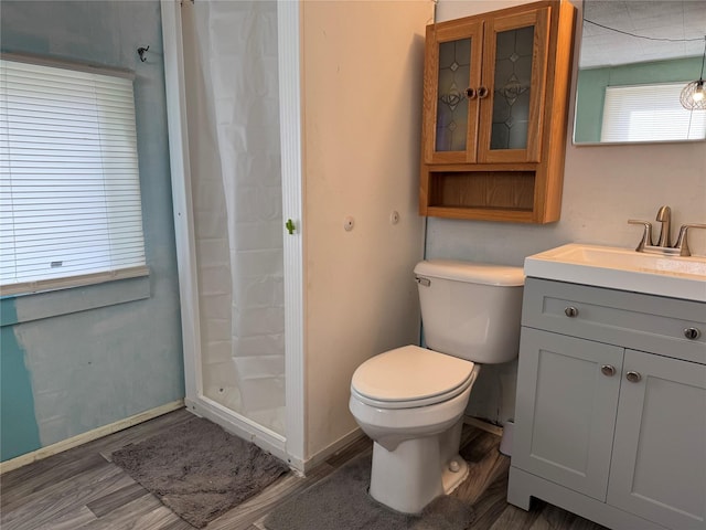 full bathroom with vanity, wood finished floors, baseboards, a shower stall, and toilet