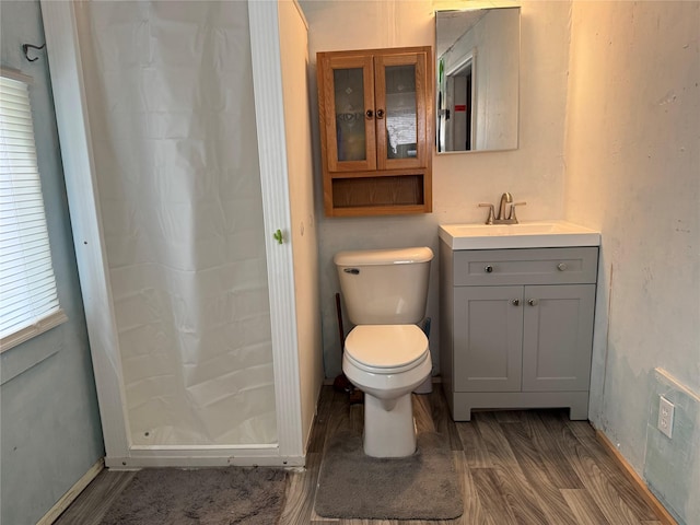 bathroom featuring a shower stall, baseboards, toilet, wood finished floors, and vanity