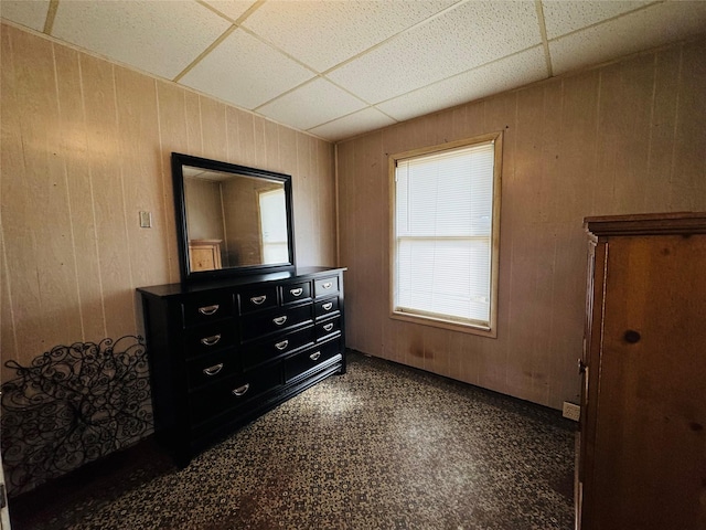 bedroom with a paneled ceiling and wood walls