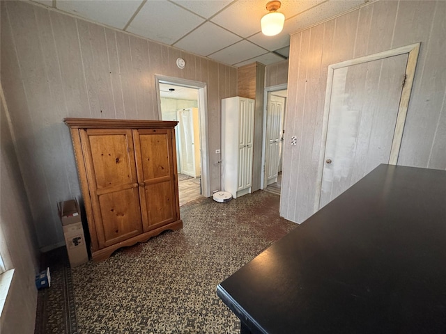 hall featuring a paneled ceiling and wooden walls