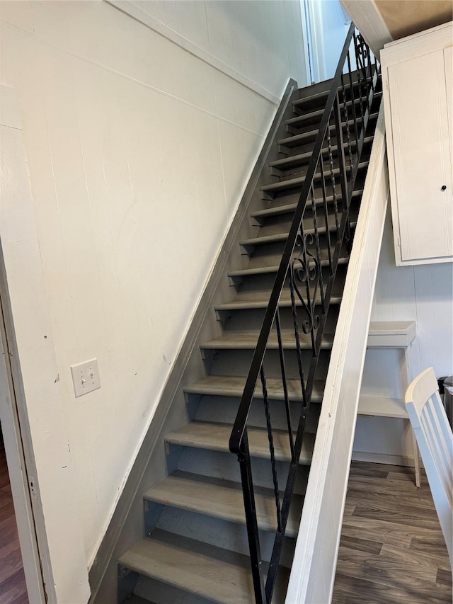 stairs with a decorative wall and wood finished floors