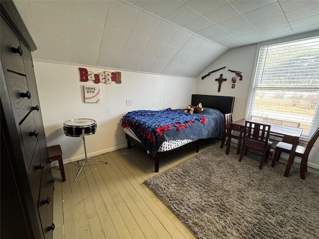 bedroom with baseboards, light wood-style floors, and vaulted ceiling