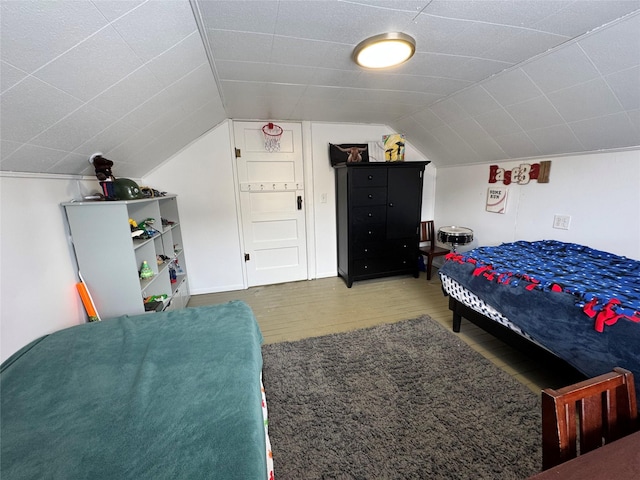 bedroom with vaulted ceiling and wood finished floors