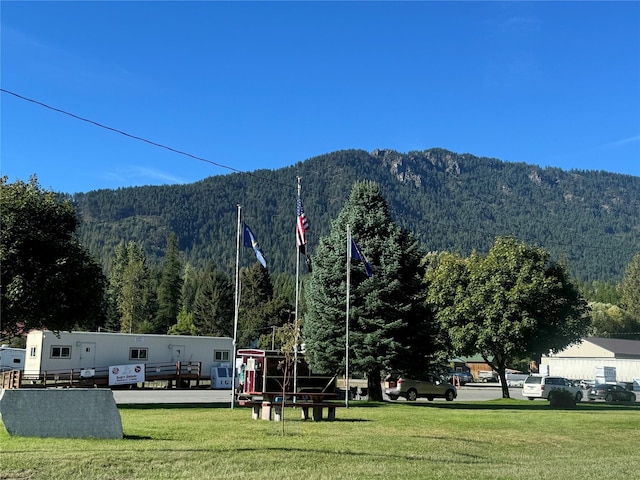 view of community with a forest view, a yard, and a mountain view